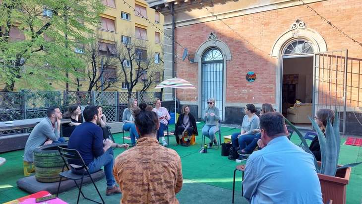 Emberek csoportja körben ül és beszélgetnek