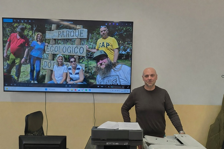 Férfi hosszú ujjú pólóban egy kivetítő előtt előadást tart