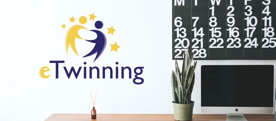 eTwinning logó egy falon mellette az asztalon növény számítógép és angol naptár