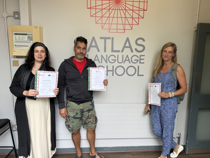 Két nő és egy férfi az oklevelét tartja fel a háttérban az ATLAS Language School felirat olvasható