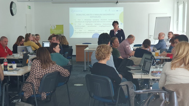 A National VET Team előadója egy kivetítő előtt előadást tart csoportmunkában dolgozó személyeknek