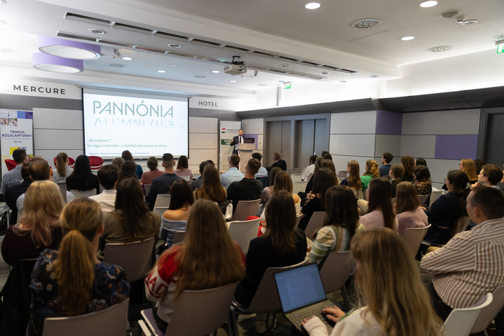 Pannónia Alumni Klub keretében a hallgatóság figyeli a kivetítő vászon mellett a terem sarkában felszólaló előadót