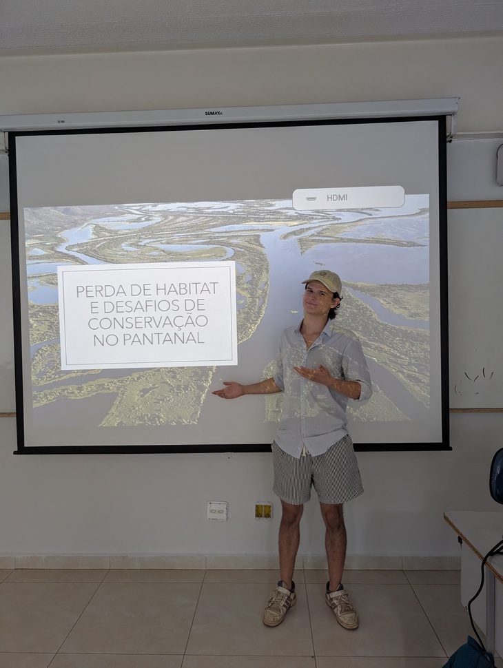 Fiatal férfi áll egy kivetítő előtt és beszámolót tart ösztöndíjas élményeiről