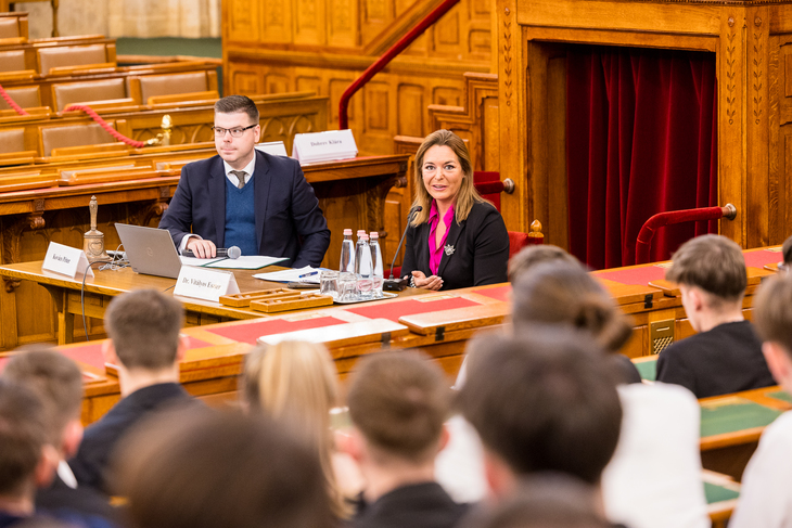 A Parlament üléstermében a pulpitus előtt ülve Dr Vitályos Eszter országgyűlési képviselő válaszol a diákok kérdéseire