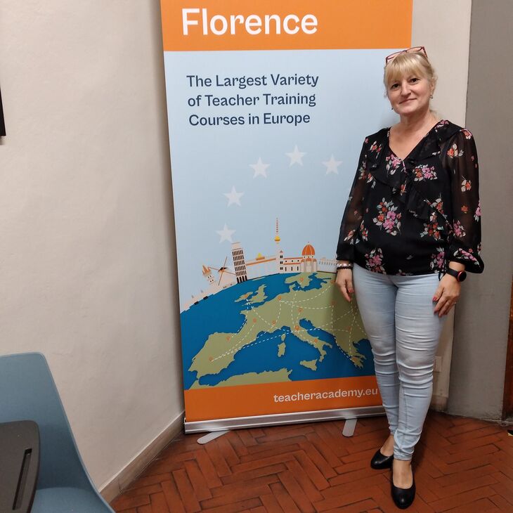 Florence felirat előtt virágos pólóban szőke hölgy áll