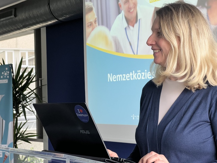 Szőke hölgy előadást tart a nemzetköziesítésről egy laptop előtt