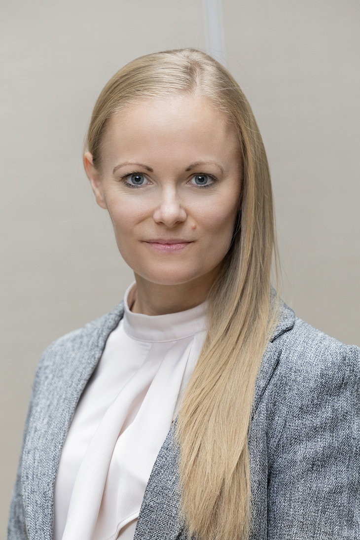 Szőke hölgy szürke zakóban és világos felsőben