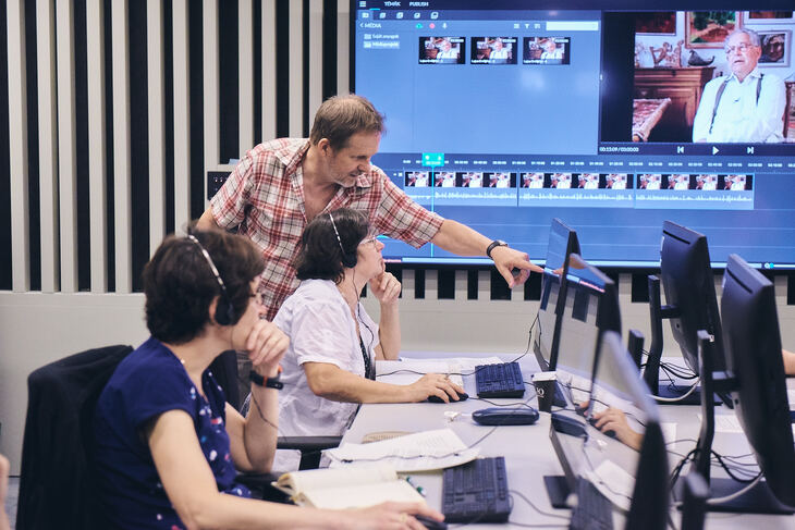 Számítógépes teremben fejhallgatóban ülő tanárok videókat néznek