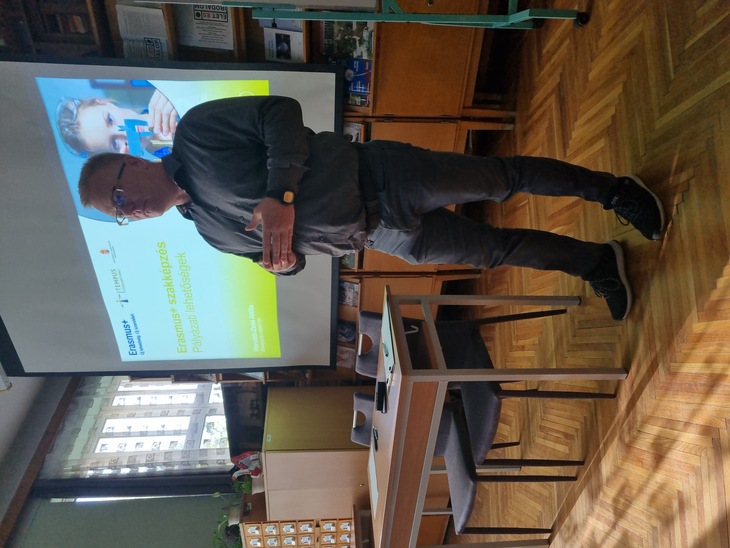 Elegánsan öltözött férfi előadást tart egy iskolában az Erasmusplusz lehetőségekről