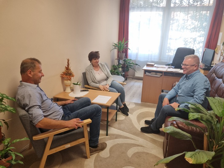 Két férfi és egy nő egy szobában ülnek és konzultálnak